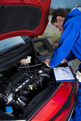 Mechanic Using Laptop While Repairing Car