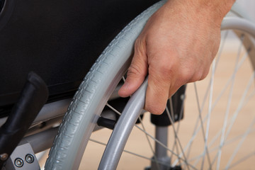 Handicapped Man's Hand Pushing Wheel Of Wheelchair