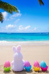 Fototapeta na wymiar Easter bunny and color eggs on the beach