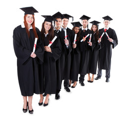 Graduate students standing in row holding diplomas