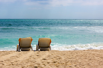 Two lonely chairs are overlooking ocean waves.