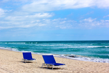 Lonely blue chairs on the ocean beach.