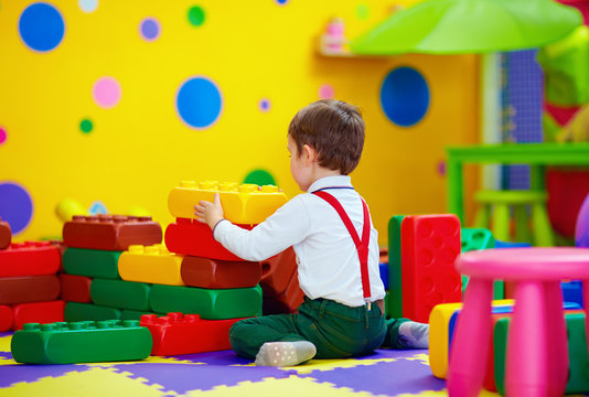 happy kid playing with toy blocks in kindergarten