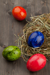 Easter eggs in hay nest on dark wood