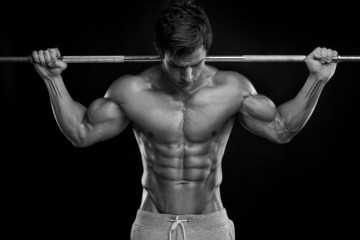 Muscular bodybuilder guy doing exercises with dumbbells over bla