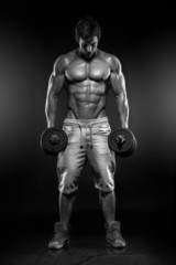 Fototapeta na wymiar Muscular bodybuilder guy doing exercises with dumbbells over bla
