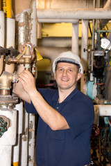Engineer with hard hat works on boiler