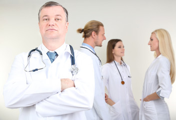 Doctor standing in front of coworkers on grey background