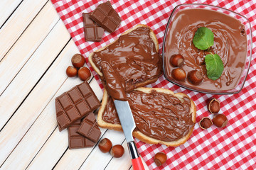 Bread with sweet chocolate hazelnut spread on wooden background