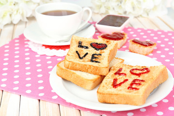Delicious toast with jam and cup of tea on table close-up