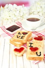 Delicious toast with jam and cup of tea on table close-up