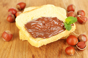 Bread with sweet chocolate hazelnut spread on wooden background