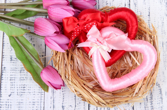 Decorative hearts in nest, on color wooden background