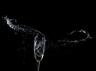 Glass of champagne with splash, on black background