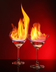 Glasses with burning alcohol on red background