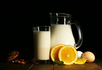 Eggnog with milk and eggs on table and black background