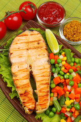 Tasty grilled salmon with vegetables, on bamboo mat
