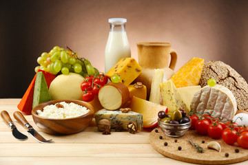 Tasty dairy products on wooden table, on dark background