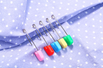 Safety pins on fabric background