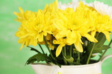 Beautiful chrysanthemum flowers in pitcher on wooden background