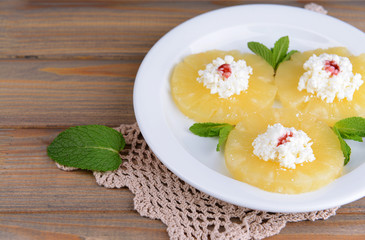 Tasty pineapple with cottage cheese on  wooden table