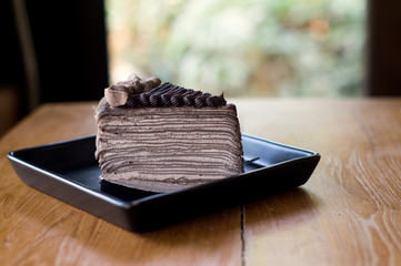 Chocolate Crepe cake and fork in black square dish on wood table