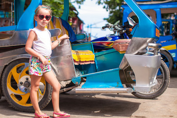 Little girl near local transport threecycles in the Asian