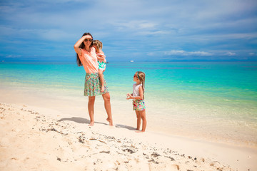 Naklejka premium Young mother and her cute daughters have fun on exotic beach