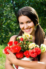 Girl in the garden with flowers,with a vase of red yellow roses.