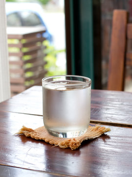 glass of water with ice on wooden table