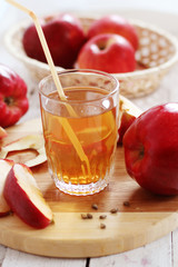  glass of apple juice with apples in the background
