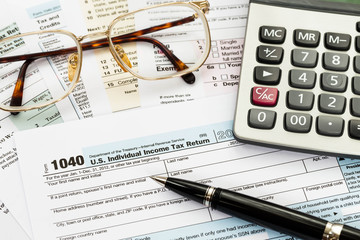 Tax form with pen, glasses, and calculator taxation concept
