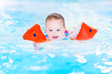 Happy laughing toddler girl having fun in a swimming pool