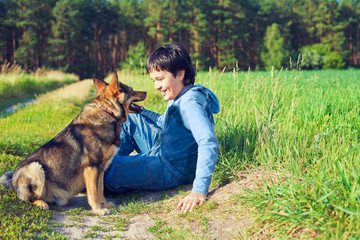 Little boy sitting with his dog on the meadow