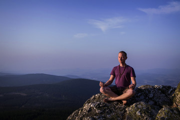 man meditating on a rock