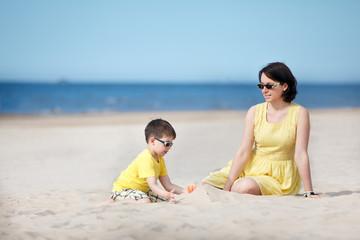 Young mother and son playing on sand beach