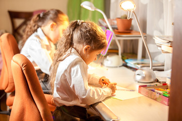 Two little girls drawing pictures behind desk