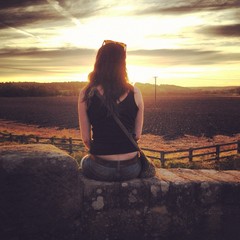 girl enjoying sunset sitting on wall in yorkshire