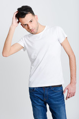 Serious young man standing against white background