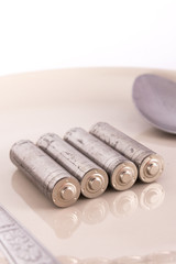 isolated of old AA battery in food dish is energy consumption co