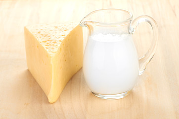 Big piece of cheese, glass jug with milk