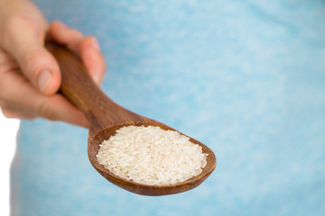Hand holding wooden spoon with rice