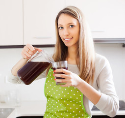 Blonde woman pouring fresh quass into glass