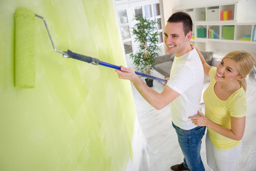 Couple painting wall with paint roller