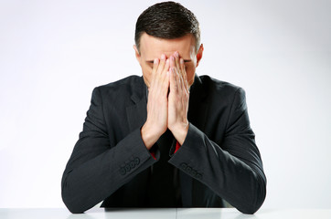Frustrated businessman sitting at the table with hands on face
