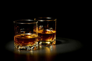 Two glasses of whiskey on black table