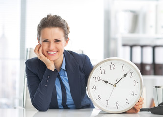 Happy business woman showing clock