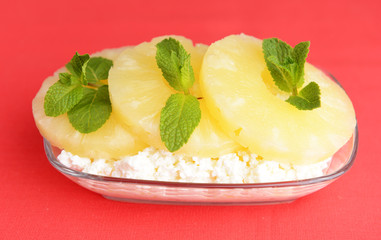 Bowl of tasty cottage cheese with pineapple, on red background