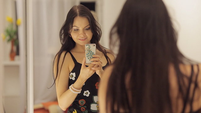 Young girl dances and takes a photo of herself before the mirror