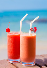 picture of two cocktails on a table near beach. party